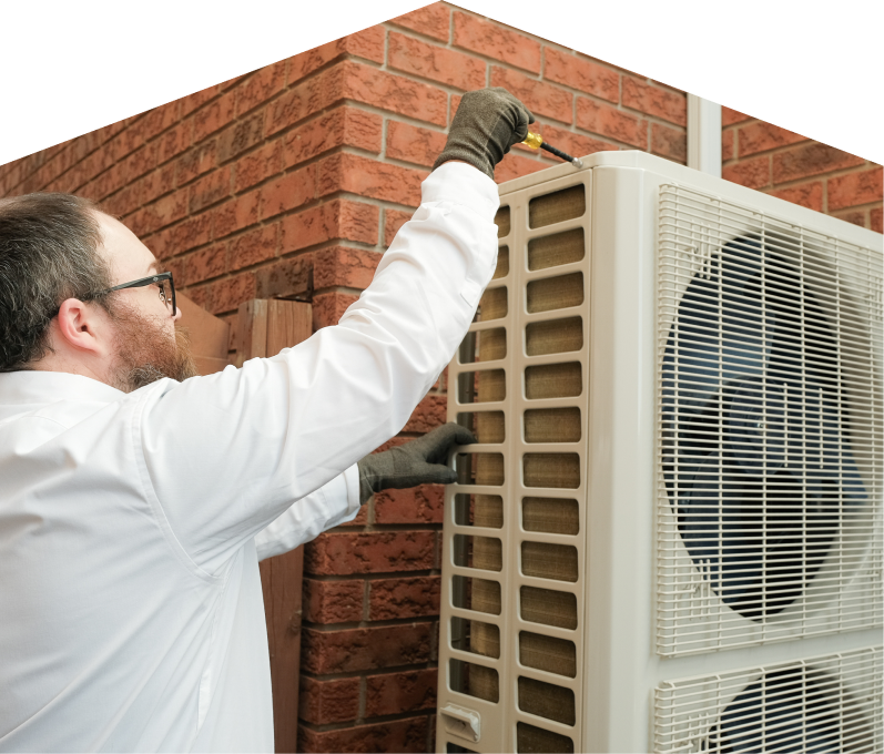 Mersey HVAC specialist using a screwdriver to complete a heat pump installation beside a brick wall. Mersey HVAC specialist using a screwdriver to complete a heat pump installation beside a brick wall.